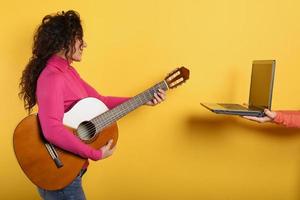 contento mujer sigue un guitarra lección en línea. amarillo antecedentes foto