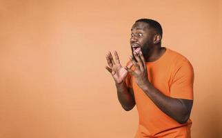 Amazed and shocked expression of a boy over orange background photo