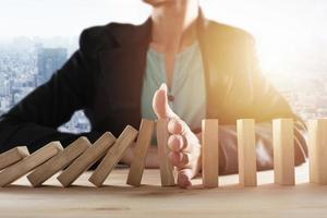 Businesswoman stops a chain fall like domino game. Concept of preventing crisis and failure in business. photo