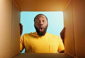 Happy man receives a package from online shop order. happy and surprised expression. Blue background. photo