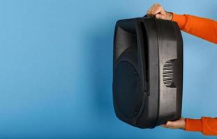 Man holds a big sound box to listen music. blue background photo