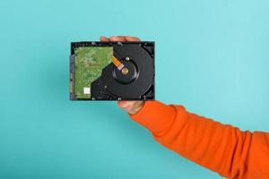 Man holds an hard disk. concept of storage and memory. cyan background photo