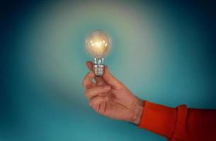 Man holds a lightbulb in hand. concept of creativity and solution. cyan background photo