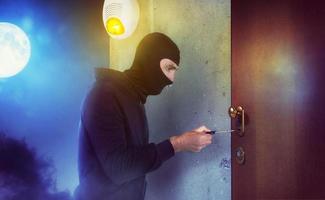 Thief with balaclava tries to open the door of apartment with a key photo