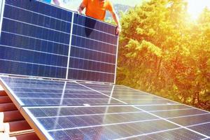 Workers assemble energy system with solar panel for electricity and hot water photo