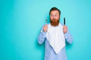 Man with tattoos is ready to eat with cutlery in hand photo