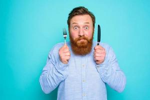 Man with tattoos is ready to eat with cutlery in hand photo
