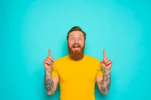 Man with yellow t-shirt and beard is shocked about something photo