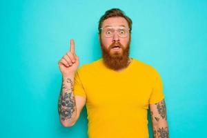 Man with yellow t-shirt and beard is shocked about something photo