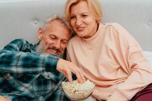 Husband and wife watch a film on the bed and eat popcorn photo