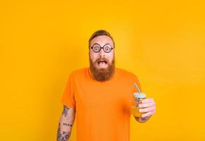 nerd temeroso hombre con lentes bebidas un Fruta jugo foto