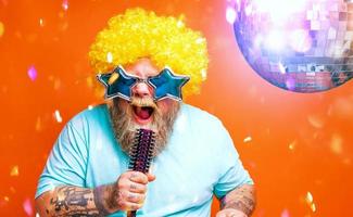 Fat man with beard, tattoos and sunglasses sings a song photo