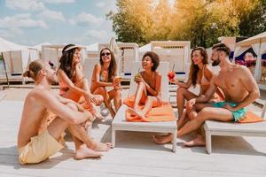 Group of friends with swimsuit drink a cocktail in a beach place photo