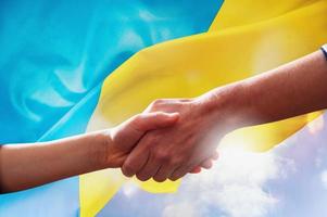 Sunny Ukraine country flag with helping hand as support photo