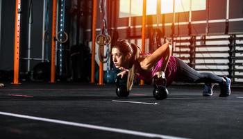 atlético niña trabajos fuera a el gimnasio con un pesas rusas foto