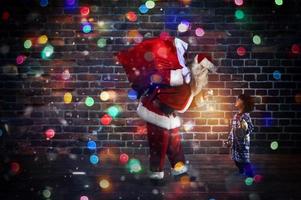 Santa Claus is giving a present for Christmas to a little boy photo