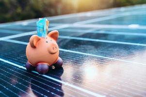 Piggybank on solar panel concept of money saved by using clean energy photo