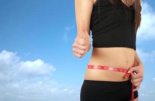 Girl on a diet holding a measuring tape around her body photo