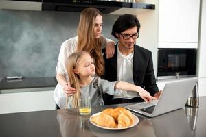 Happy little girl watching a movie on the computer with her father and mother photo