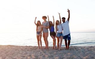 Group of friends having fun on the beach. Concept of summertime photo