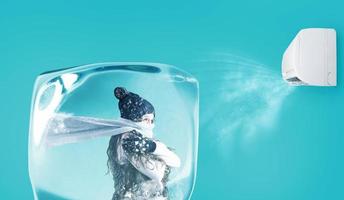 Woman frozen in an ice cube under the air jet of an air conditioner on cyan background photo