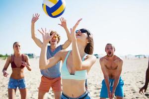 Group of friends playing at beach volley at the beach photo