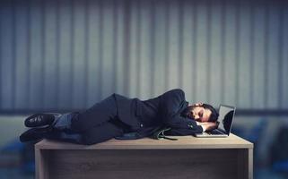 Businessman sleeping over a desk due to overwork photo