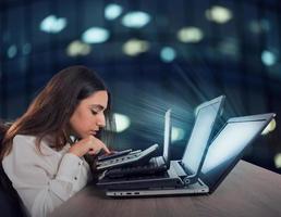Businesswoman works with multiple devices, smartphone, calculator and laptops. Concept of overwork and stress photo