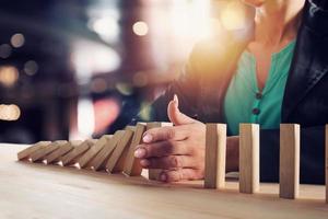 Businesswoman stops a chain fall like domino game. Concept of preventing crisis and failure in business. photo