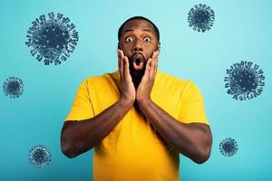 Fearful expression of a boy who is scared to catch the coronavirus. Cyan background. photo