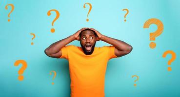 Feared and shocked expression of a boy with many questions . cyan colored background photo