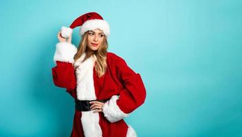 Blonde girl with Santa Claus costume on cyan background photo
