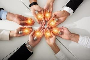 Teamwork and brainstorming concept with businessmen that share an idea with a lamp. Concept of startup photo
