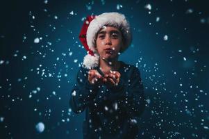 Child with Christmas hat blows to make the snow fly photo