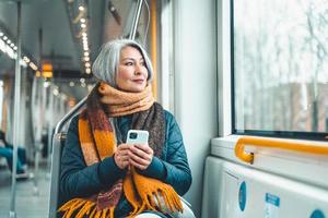 mayor mujer enviar mensaje con un móvil teléfono en un tren foto