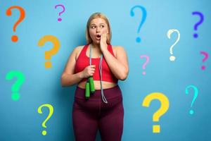 Fat girl does gym but is worried due to lot of questions. cyan background photo