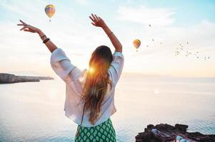 Carefree woman watches the sunset with her hands in the air photo