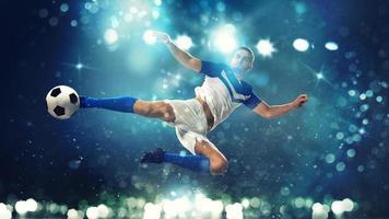 Soccer striker hits the ball with an acrobatic kick in the air on dark blue background photo