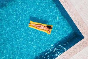 Girl in swimsuit who tan in a swimming pool photo