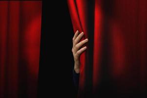 Girl opens red curtain of a theater. The show can starts photo