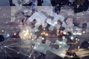 Business people join puzzle pieces in office. Concept of teamwork and partnership. double exposure with internet network effects photo