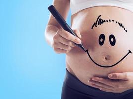 Smiley drawn on a pregnant woman stomach photo