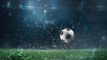 cerca arriba de un fútbol pelota laminación en el jugando campo en un lluvioso noche foto