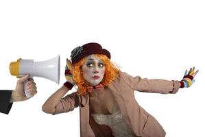 Funny clown hears a megaphone with a message. Isolated on white background photo