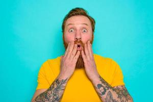 Man with yellow t-shirt and beard is worried and preoccupied photo
