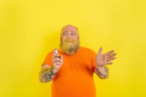 Happy man with beard and tattoos holds a hands cleaner against covid19 photo