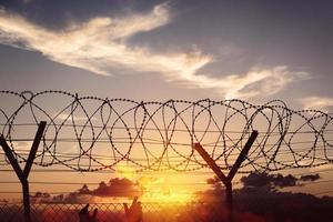 Silhouette of two hands on a fence at sunset photo