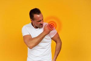 Aching man with back pain. Yellow background photo