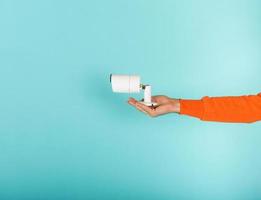 Man holds in hand an ip camera. Cyan background photo
