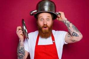 wondered chef with beard and red apron plays with pot photo